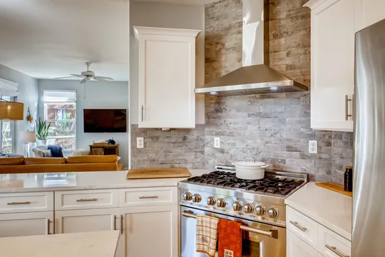 Kitchen remodel with stone backsplash and range hood by Merribuild