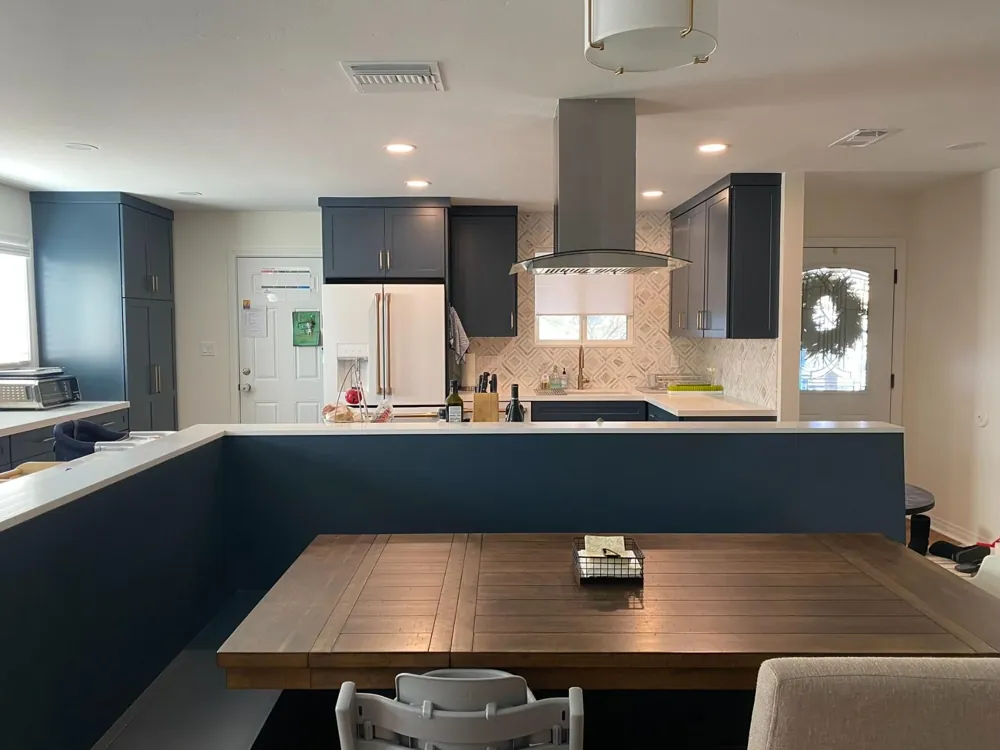 Navy kitchen with wood island and range hood by RCS Pro Build
